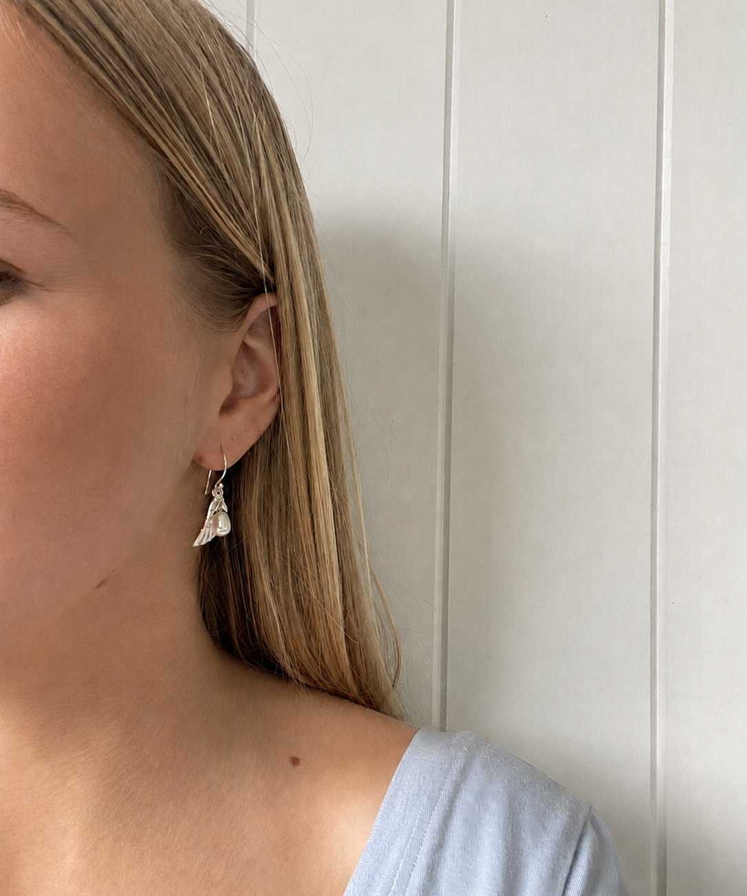 Close-up of a model wearing Angel Wing Earrings Silver with a delicate pearl drop.