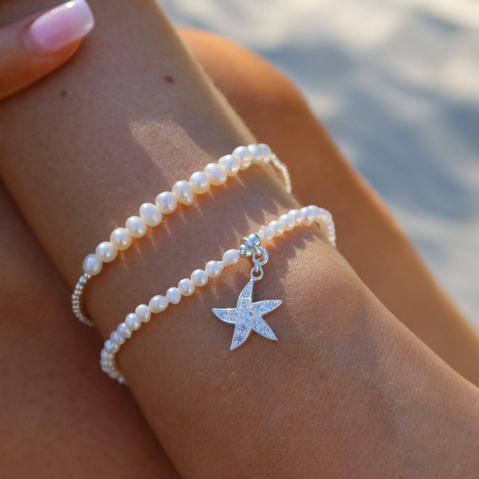 Pearl stretch bracelet with cubic zirconia starfish charm worn on wrist